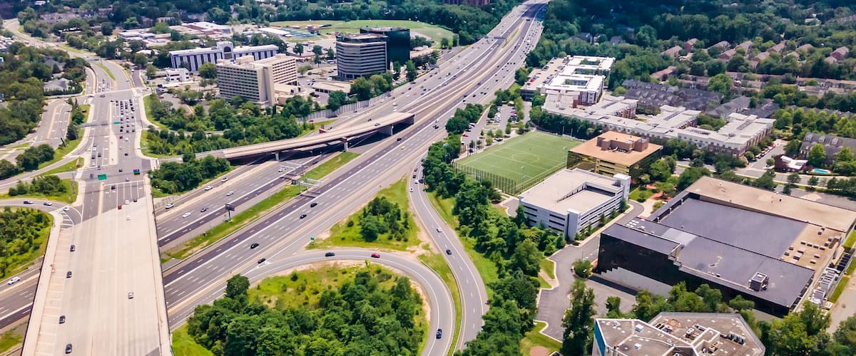 A multi-level highway interchange with surrounding urban development and greenery.