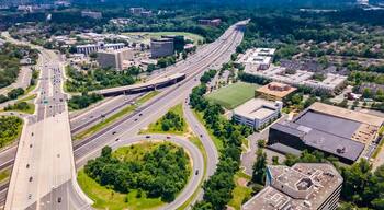 Eine mehrspurige Autobahnkreuzung mit angrenzender Stadtentwicklung und Grünflächen.