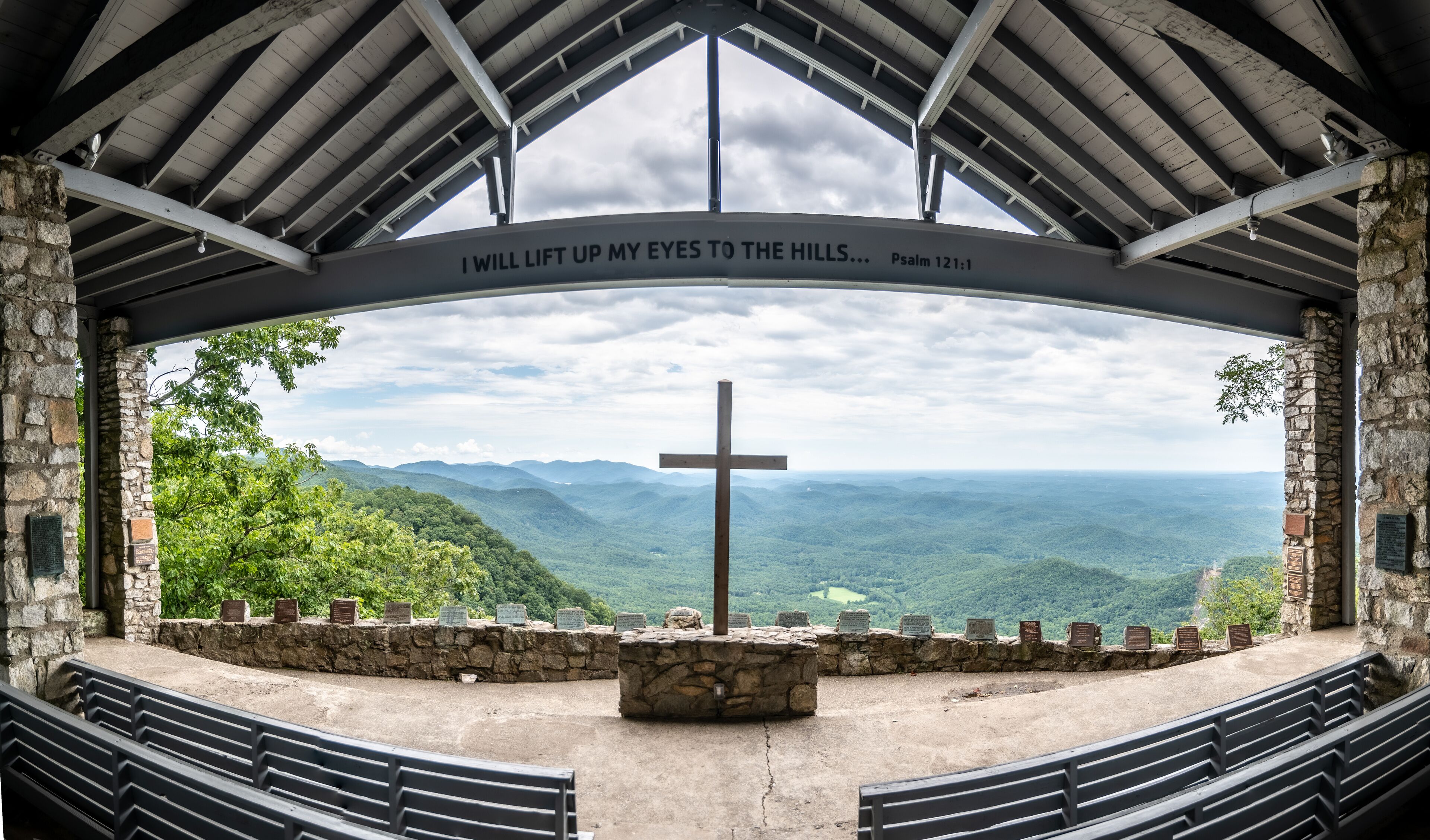 A cross in a stone structure with a view of a mountainous landscape.