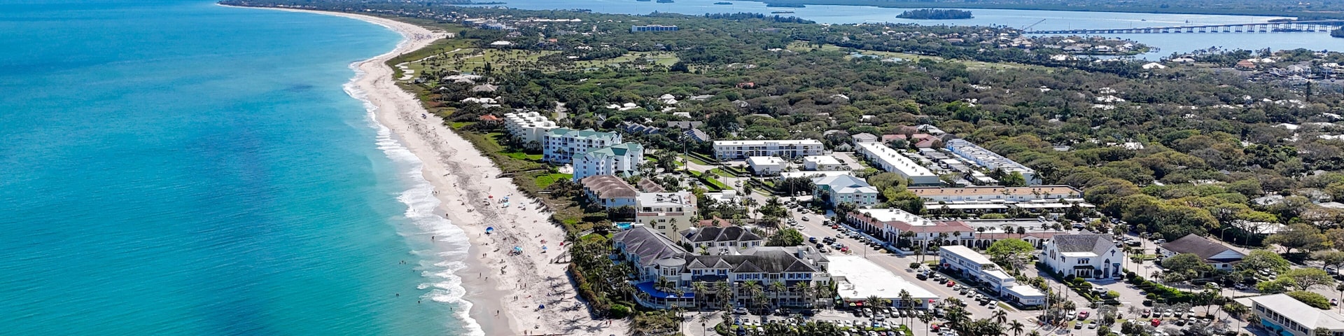 A coastal town with a beach, buildings, and a distant ship.