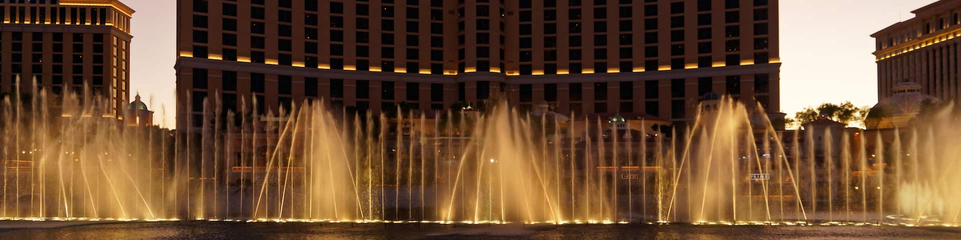 A large hotel with a fountain in front.