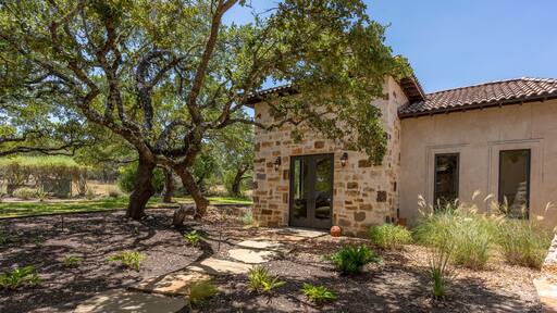 Beautiful stone house surrounded by lush greenery on a sunny day