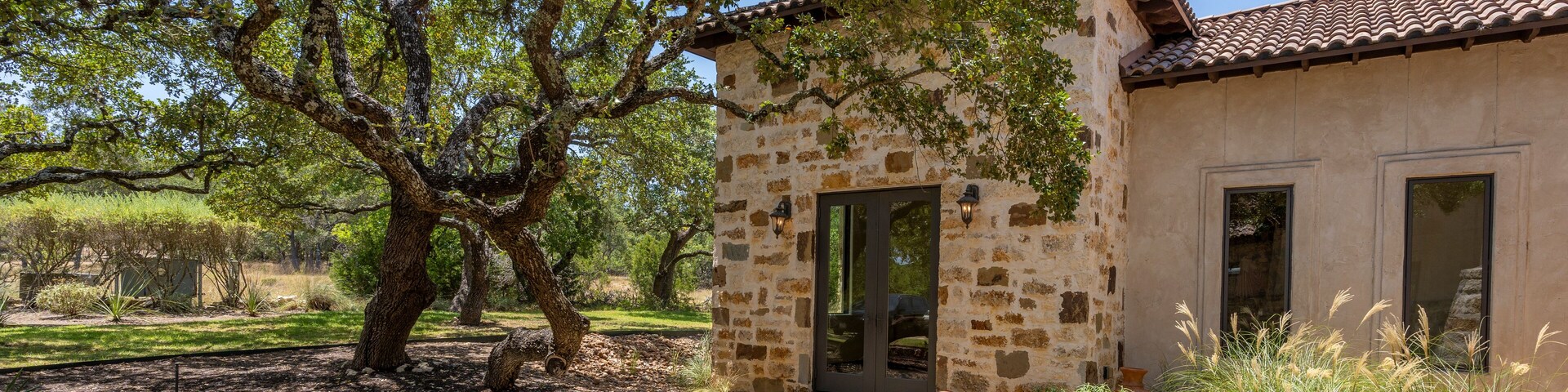 Beautiful stone house surrounded by lush greenery on a sunny day