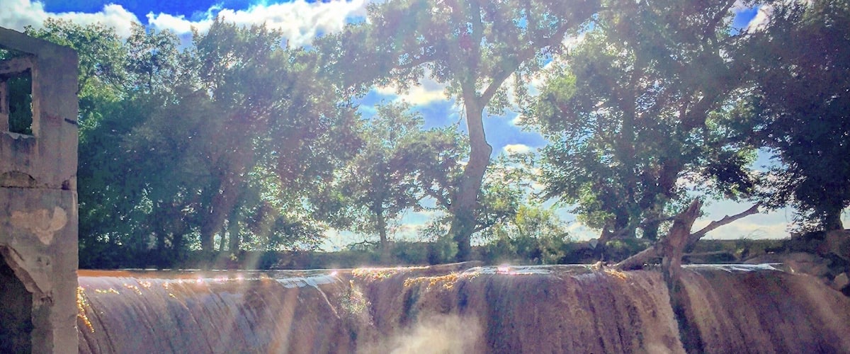 A waterfall with sunlight filtering through trees.