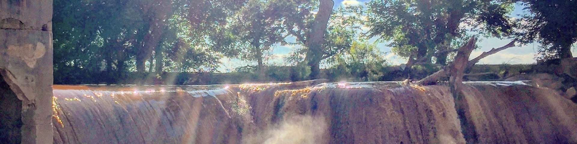 A waterfall with sunlight filtering through trees.