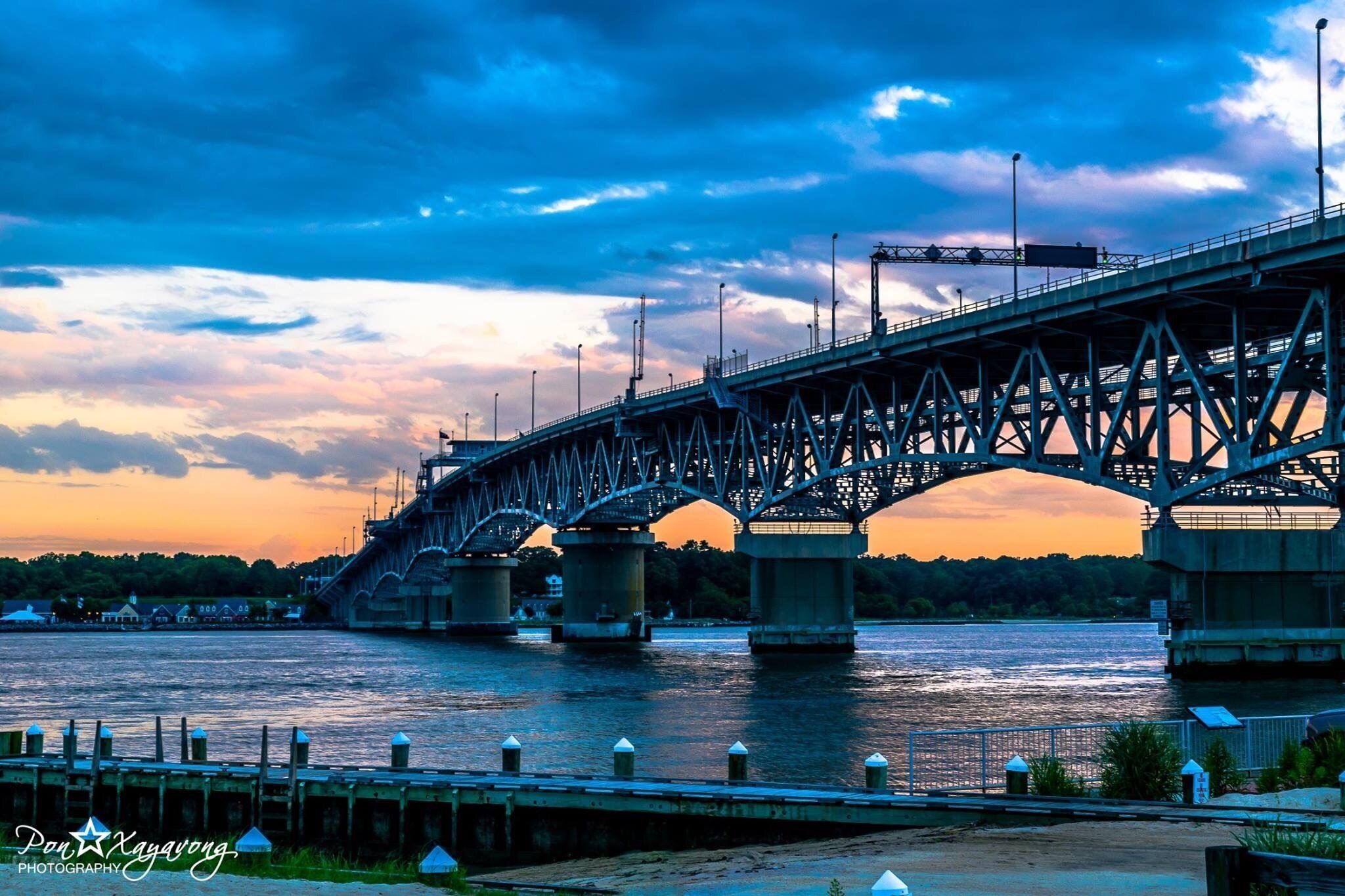 A large steel bridge spanning a river at sunset.