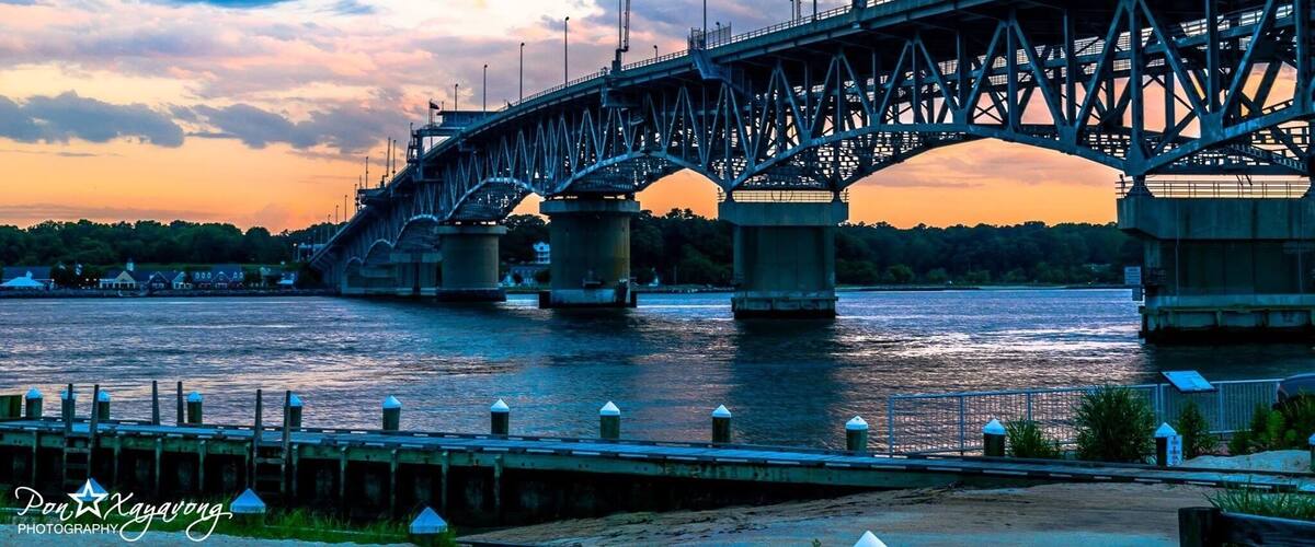 A large steel bridge spanning a river at sunset.