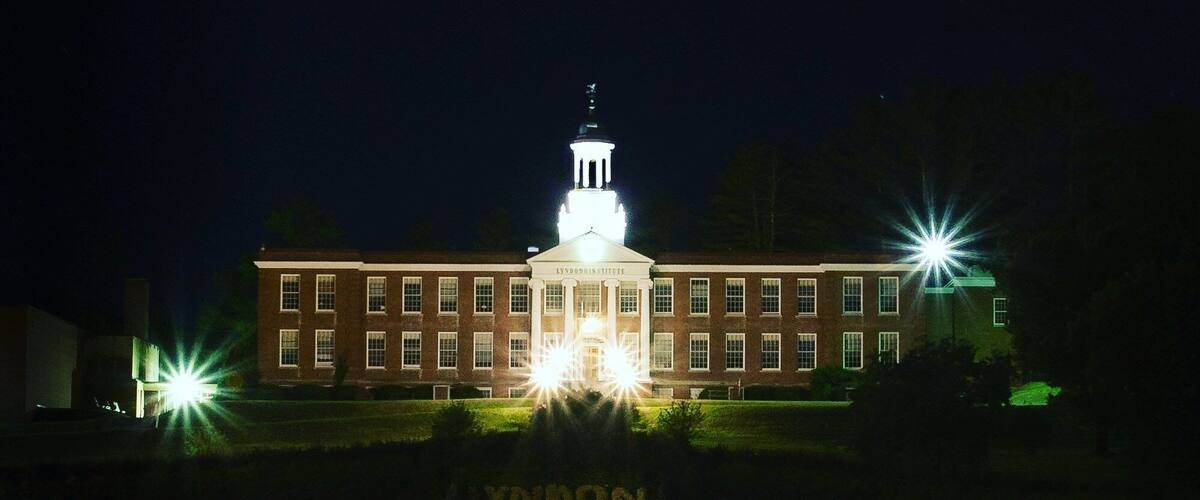 A large brick building with a central tower and two bright lights on either side.