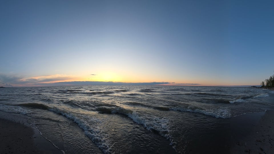 A beach with waves at sunset.