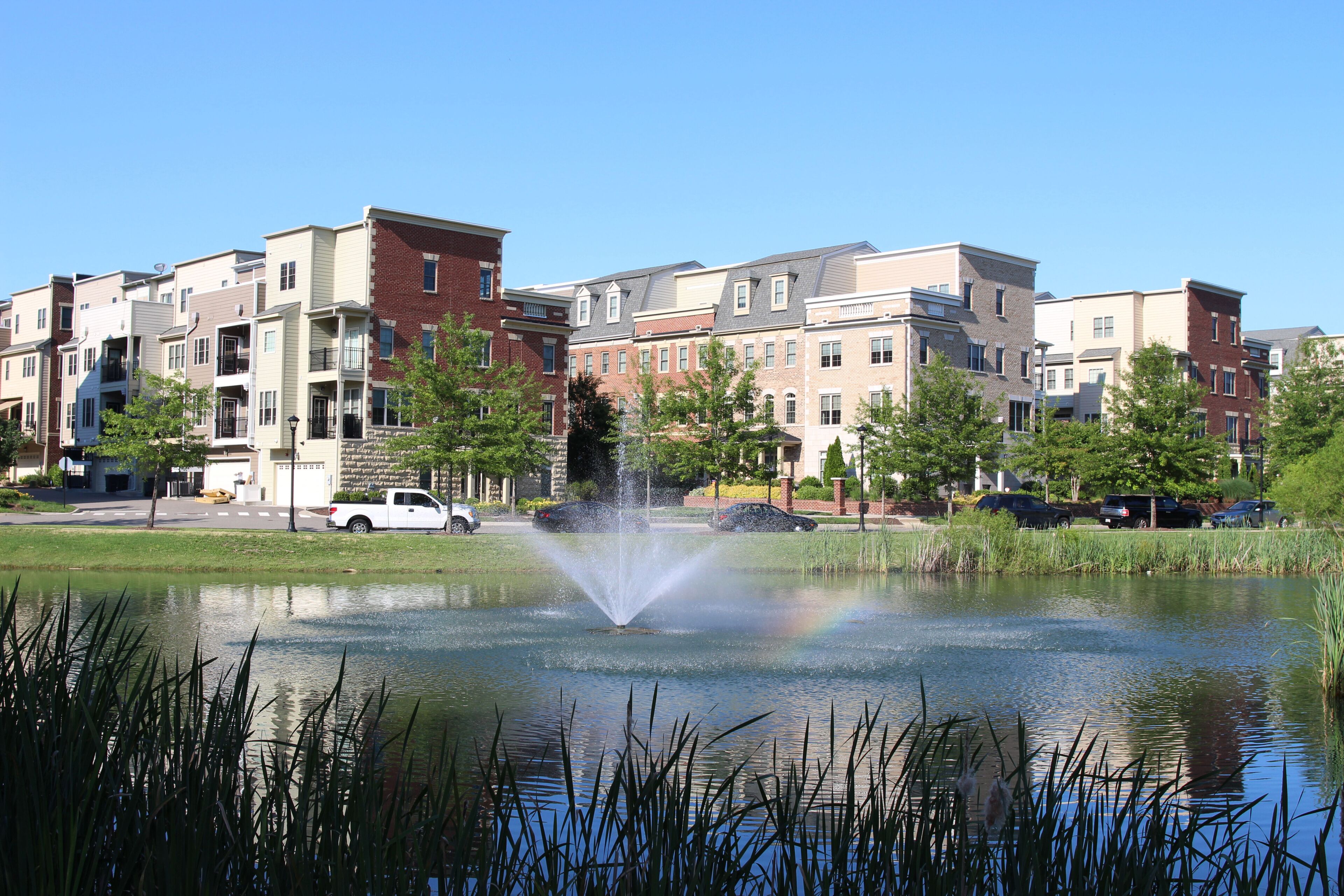 A pond with a fountain at modern townhouses in the summer. Richmond suburbs, Virginia