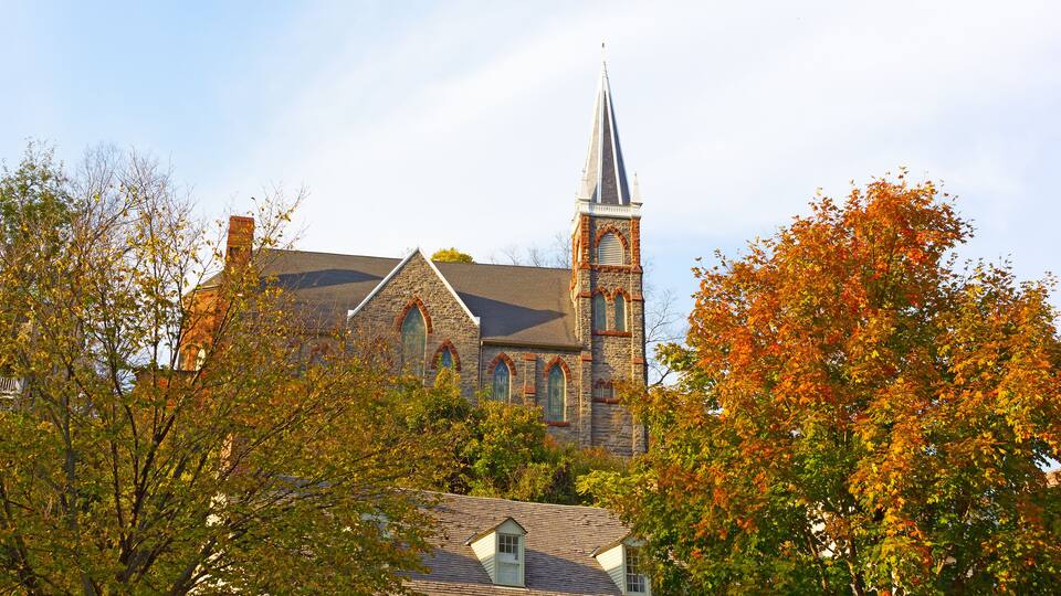 Historic city church in magnificent fall colors at Harpers Ferry, West Virginia, USA. The church on a hillside framed by maple trees.