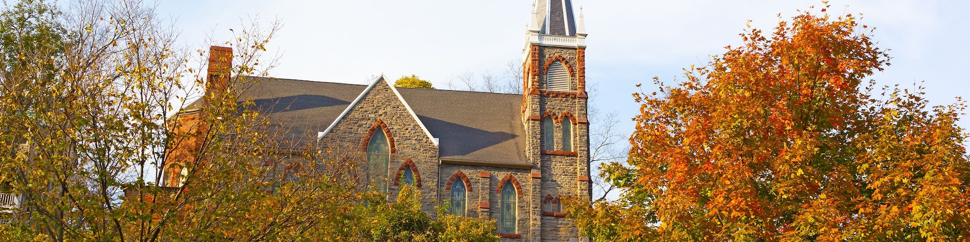 Historic city church in magnificent fall colors at Harpers Ferry, West Virginia, USA. The church on a hillside framed by maple trees.