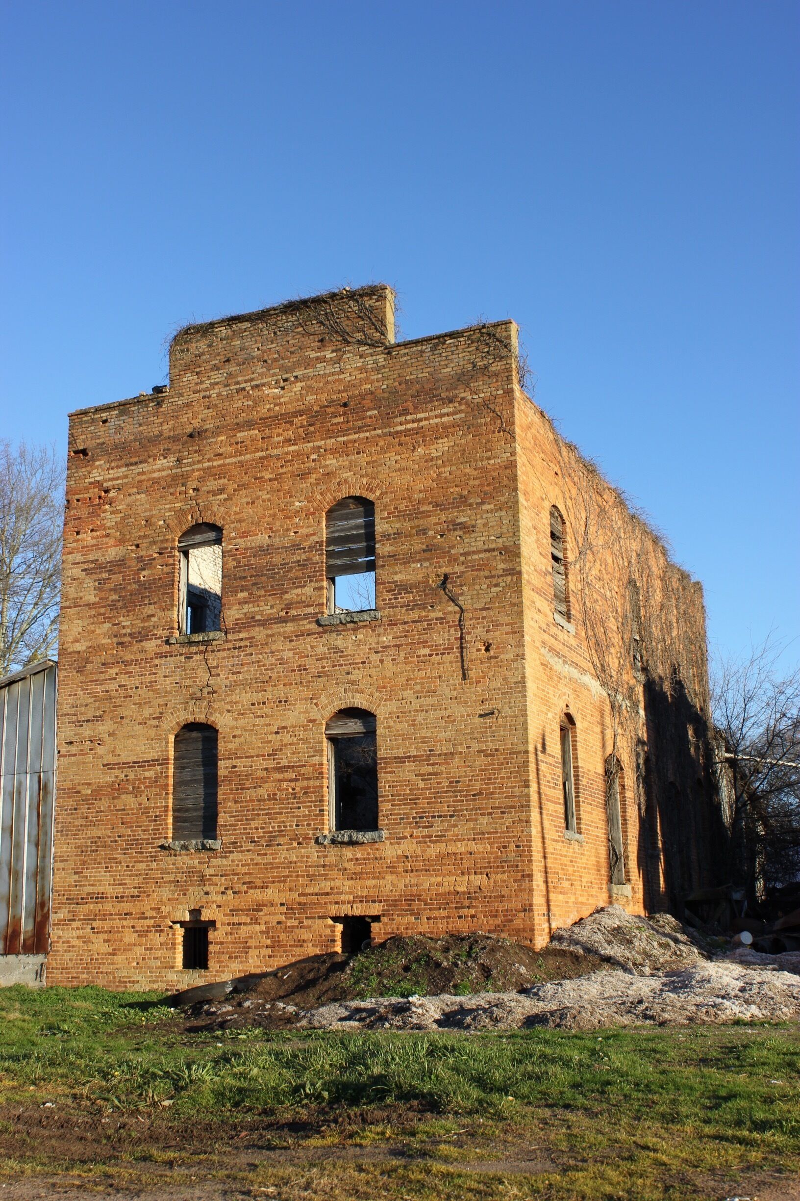 A large, unfinished brick building with multiple windows and a flat roof.