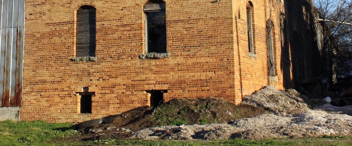 A large, unfinished brick building with multiple windows and a flat roof.