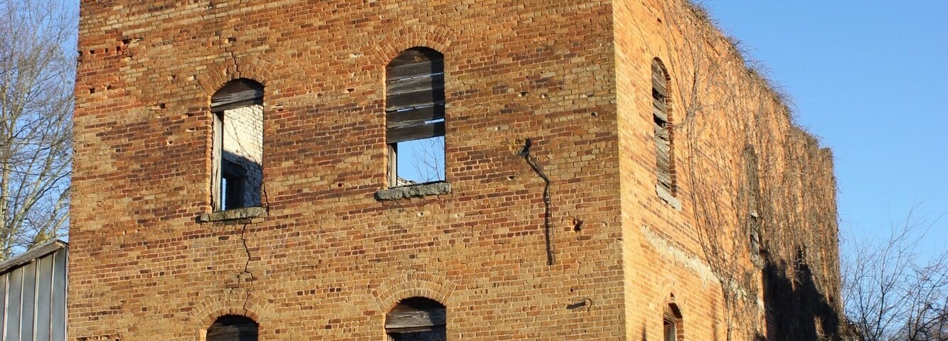 A large, unfinished brick building with multiple windows and a flat roof.