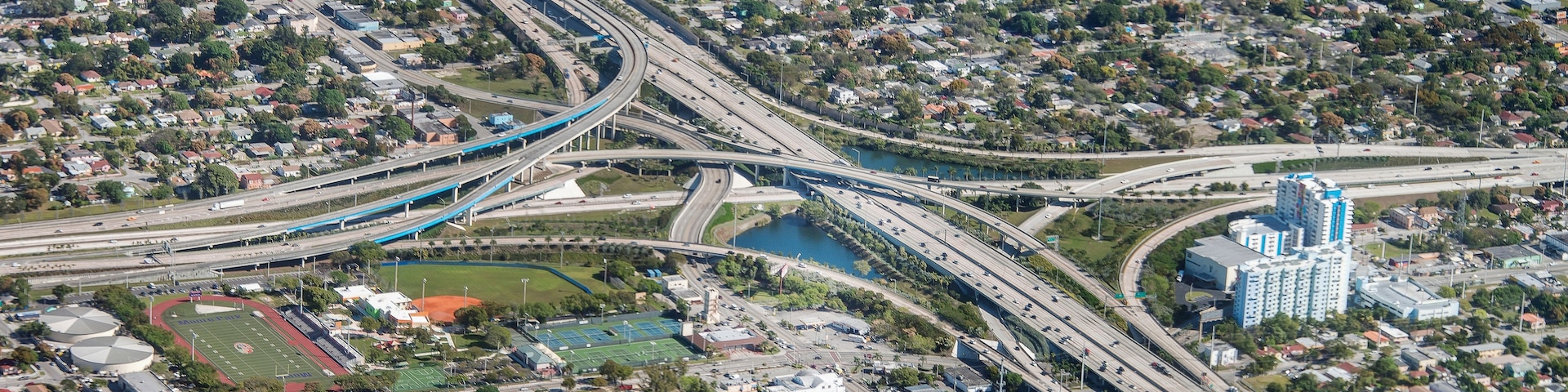 A complex highway interchange with multiple overpasses and a large body of water.