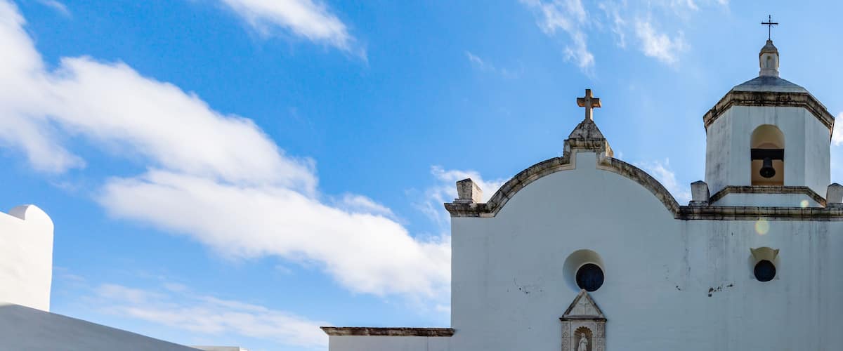 A white colonial-style building with a bell tower and arched windows.