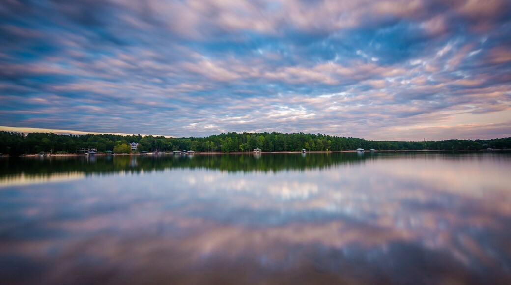 A calm lake with a reflection of the sky and trees.