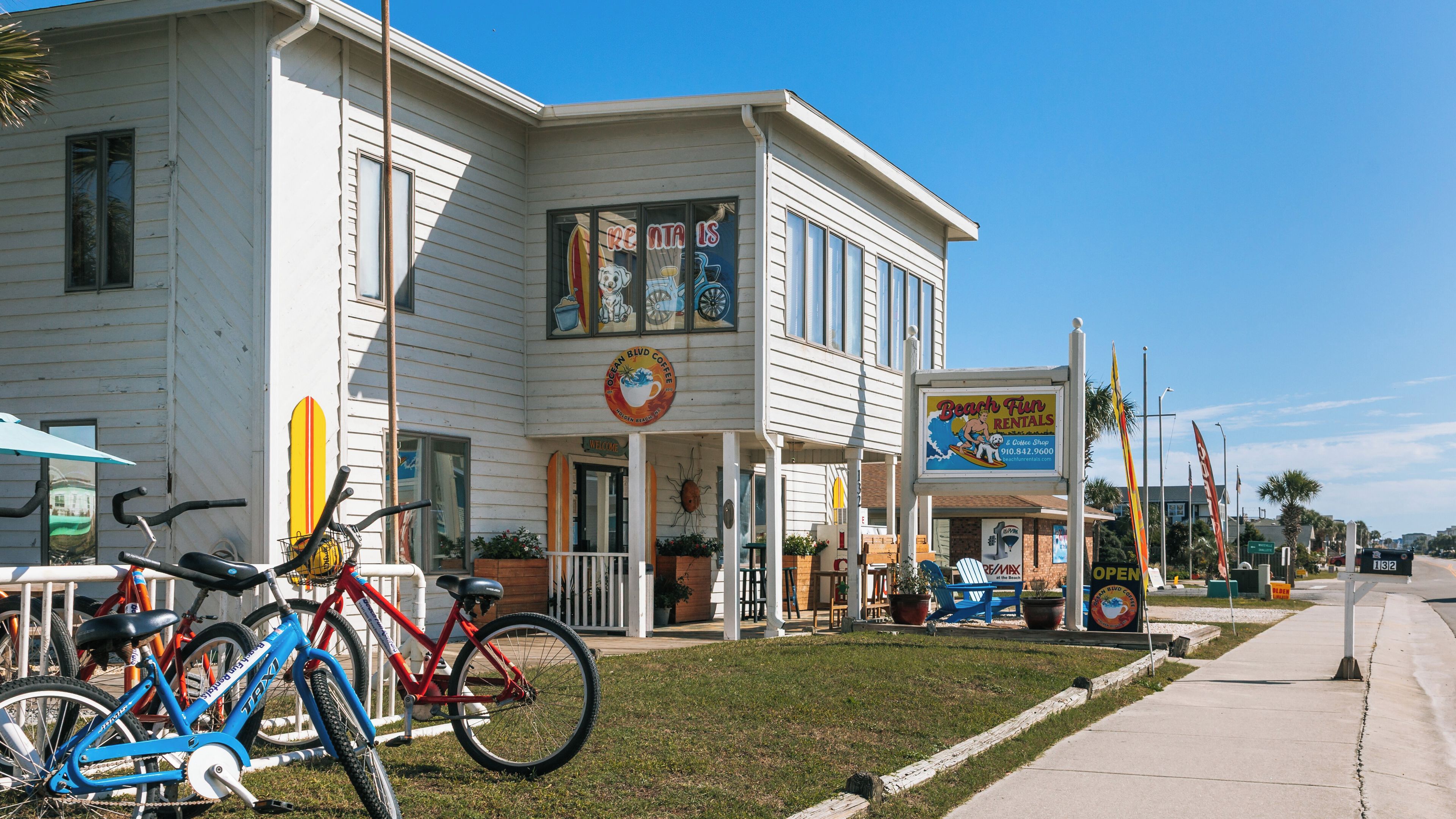 A coastal building with a sign for Ocean Blvd Coffee, a red bicycle, and a Beach Fun Rentals sign.