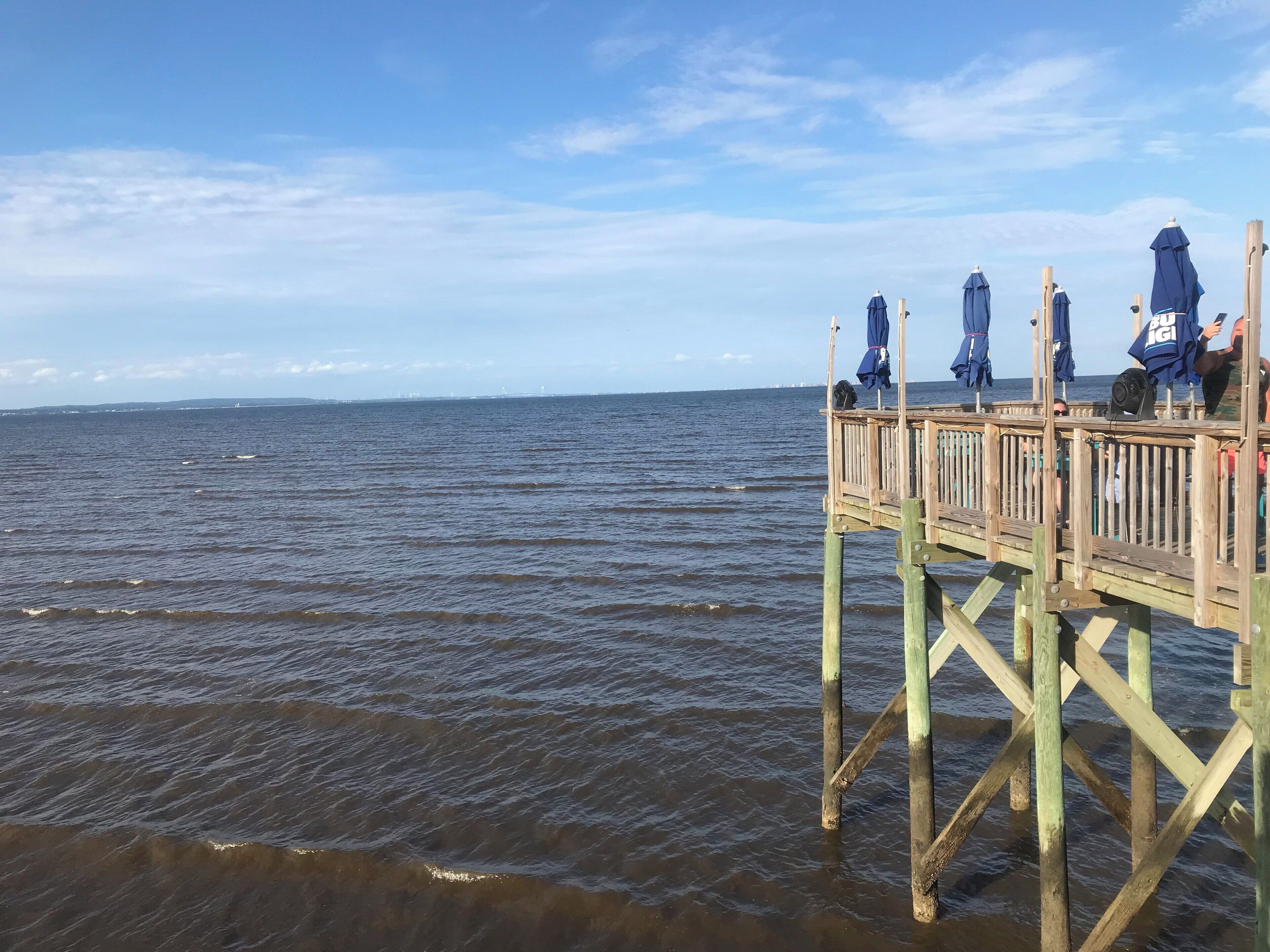 A wooden pier extending into a body of water with a clear sky.