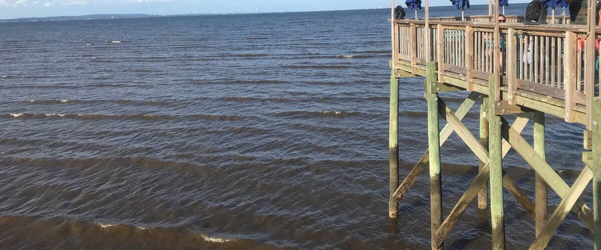 A wooden pier extending into a body of water with a clear sky.