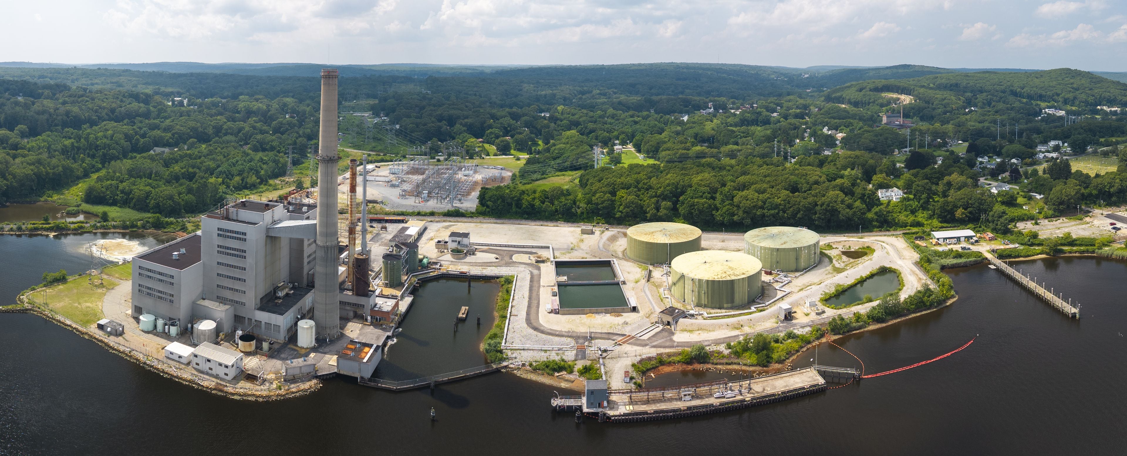 Aerial view of Generation Bridge Montville Power featuring a tall smokestack, large storage tanks, and industrial facilities on the waterfront in Montville, Connecticut, United States.