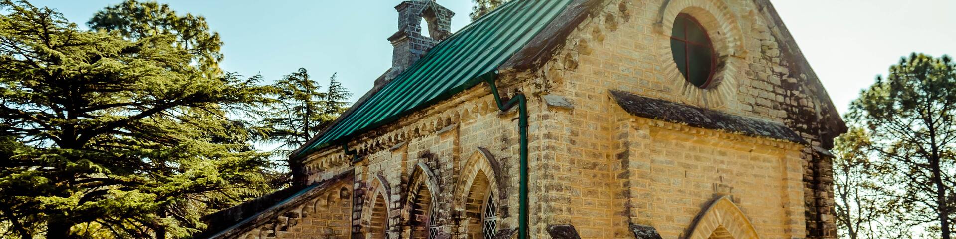 A small brick church with a green roof and arched windows.