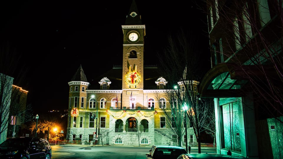 A historic building with a clock tower, adorned with festive lights and garlands.