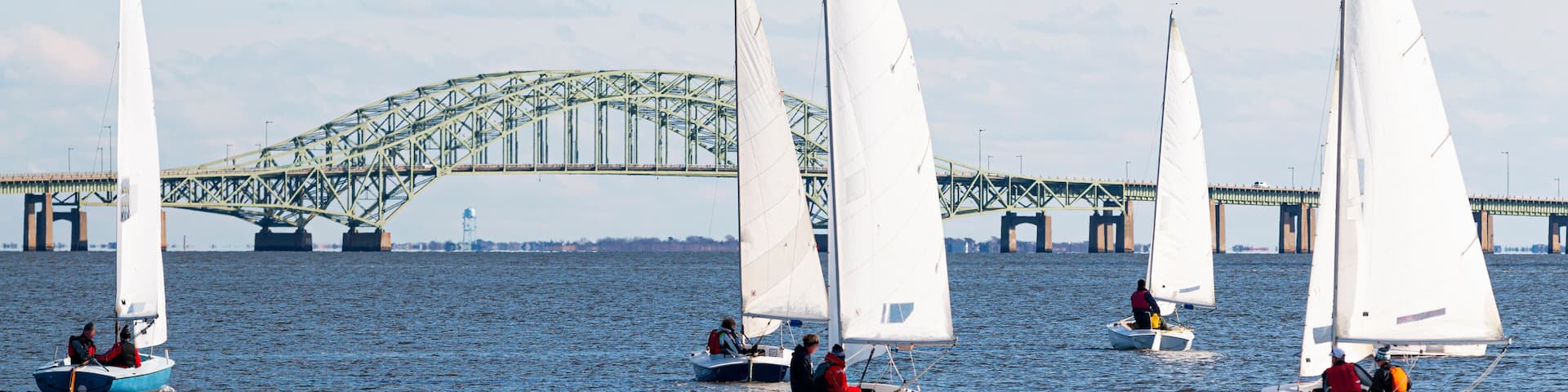 Five sailboats heading toward the Great South Bay bridge in winter