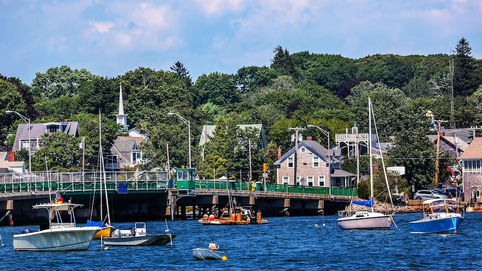 A harbor with boats, a bridge, and houses along the waterfront.