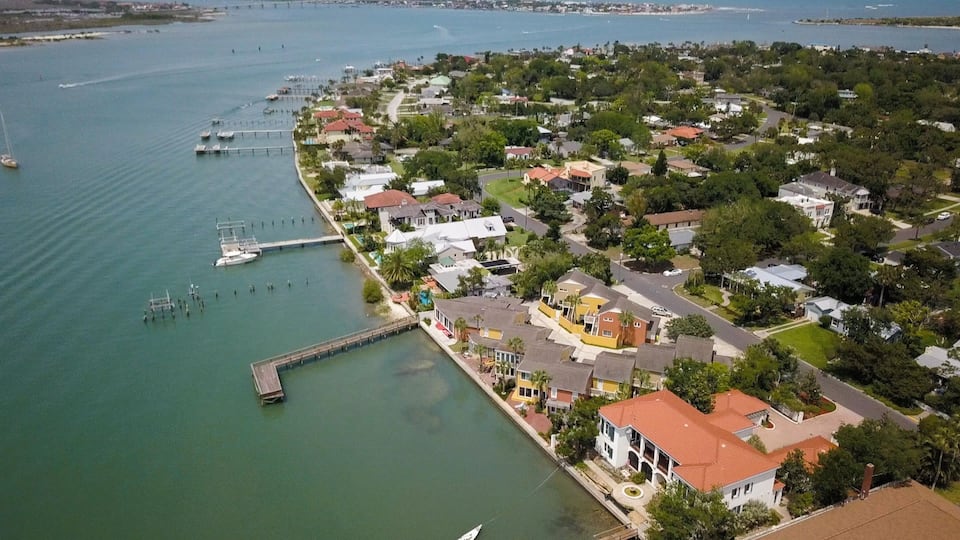 A coastal residential area with houses, a marina, and a bridge.