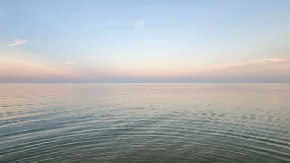 A calm sea with gentle waves under a clear sky.