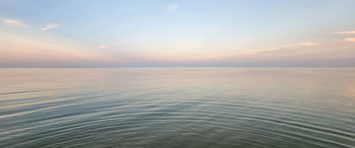 A calm sea with gentle waves under a clear sky.