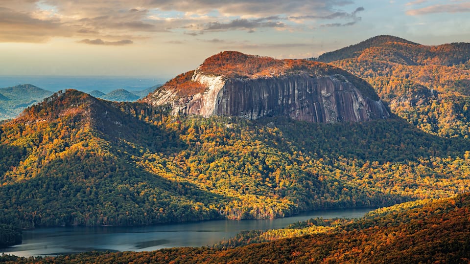 A mountainous landscape with autumn foliage, a lake, and distant hills.