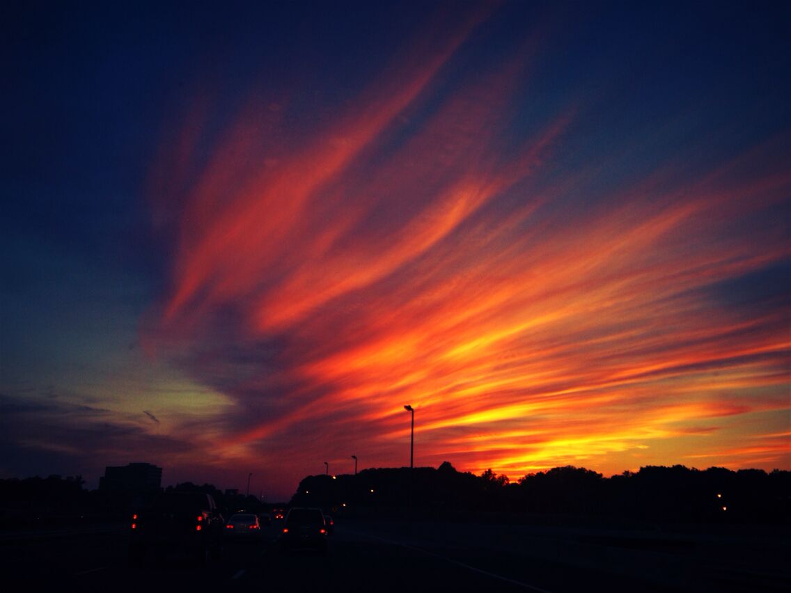 A sunset with vibrant red and orange clouds over a city skyline.