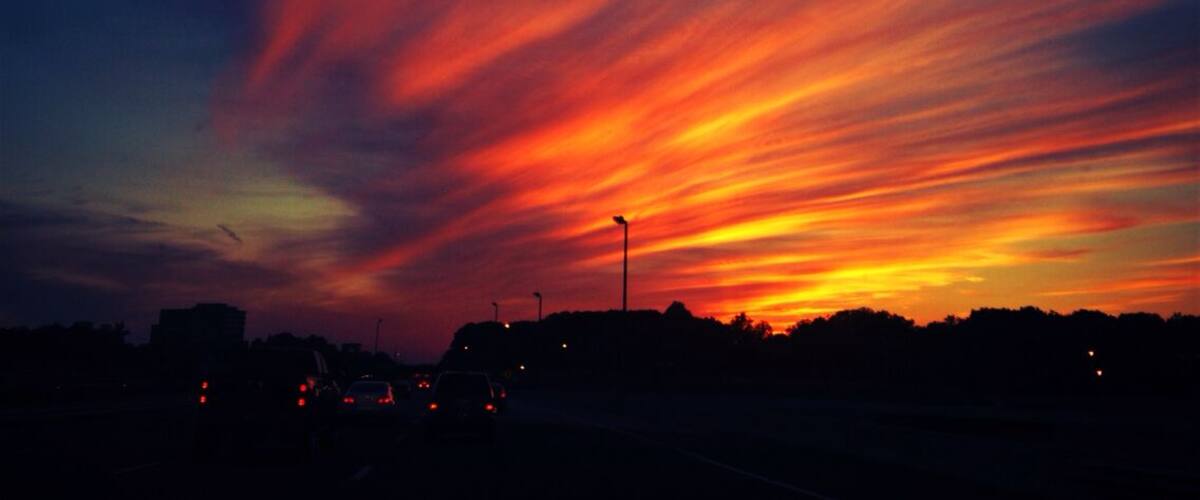 A sunset with vibrant red and orange clouds over a city skyline.