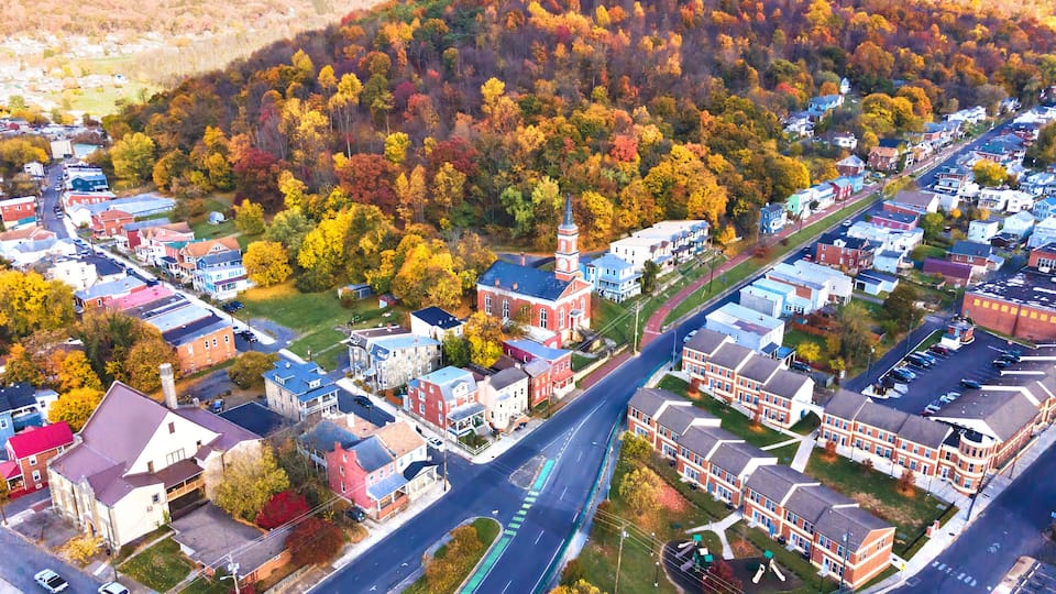 A town with autumn-colored trees, a prominent church, and a mix of residential and commercial buildings.