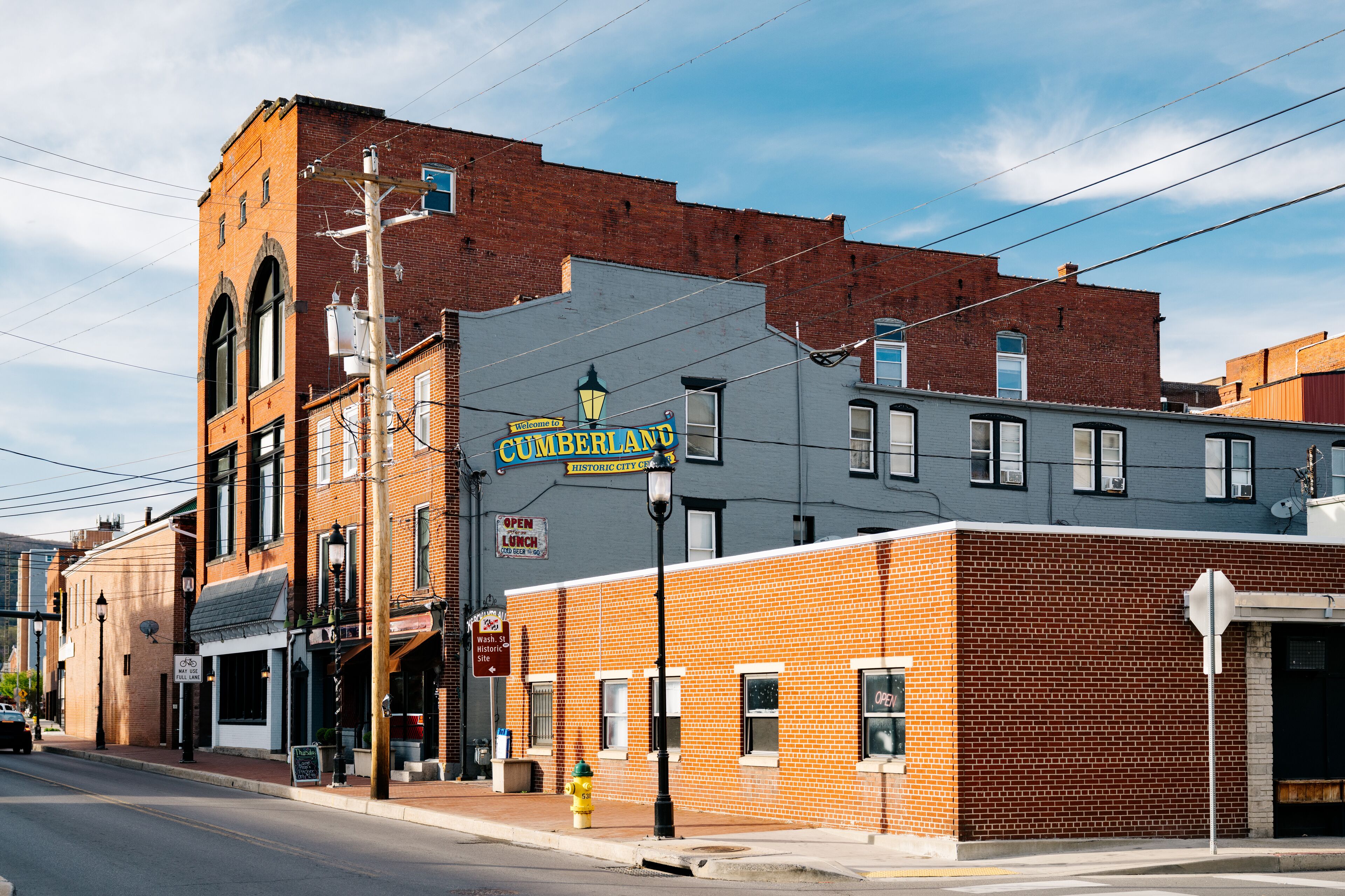A historic downtown street with brick buildings, a vintage street lamp, and a sign for Cumberland.