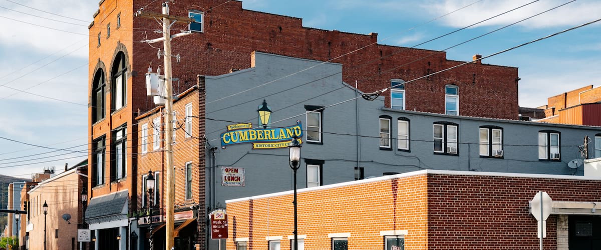 A historic downtown street with brick buildings, a vintage street lamp, and a sign for Cumberland.