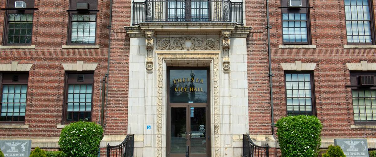 The entrance to Chelsea City Hall with a brick facade, decorative columns, and a central entrance.