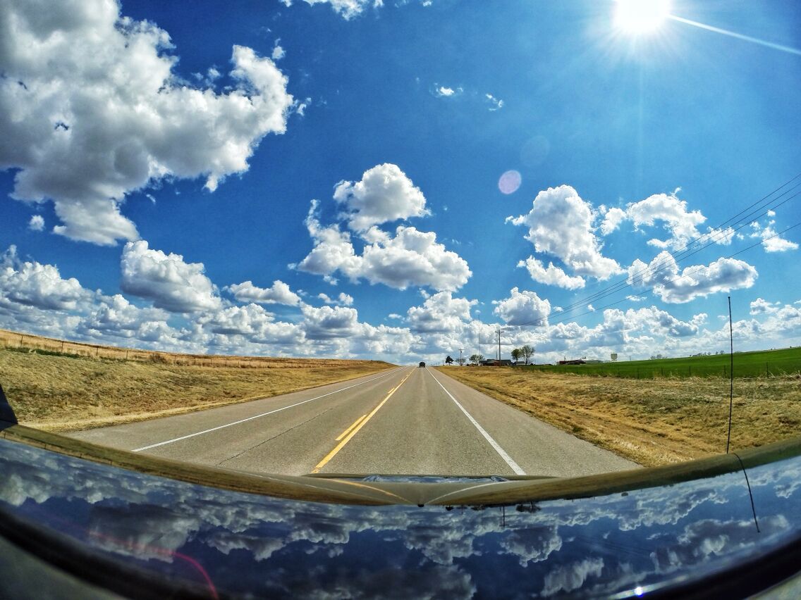 A road with a clear blue sky and scattered clouds.