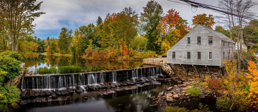 A waterfall, a stone building, and autumn foliage.