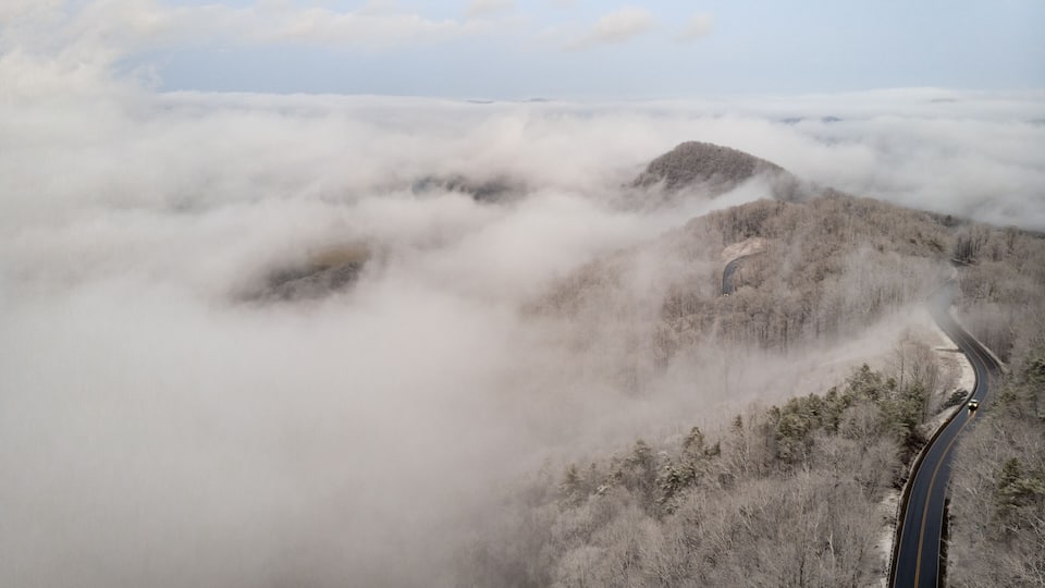 A winding road through a mountainous area with dense fog covering the peaks.