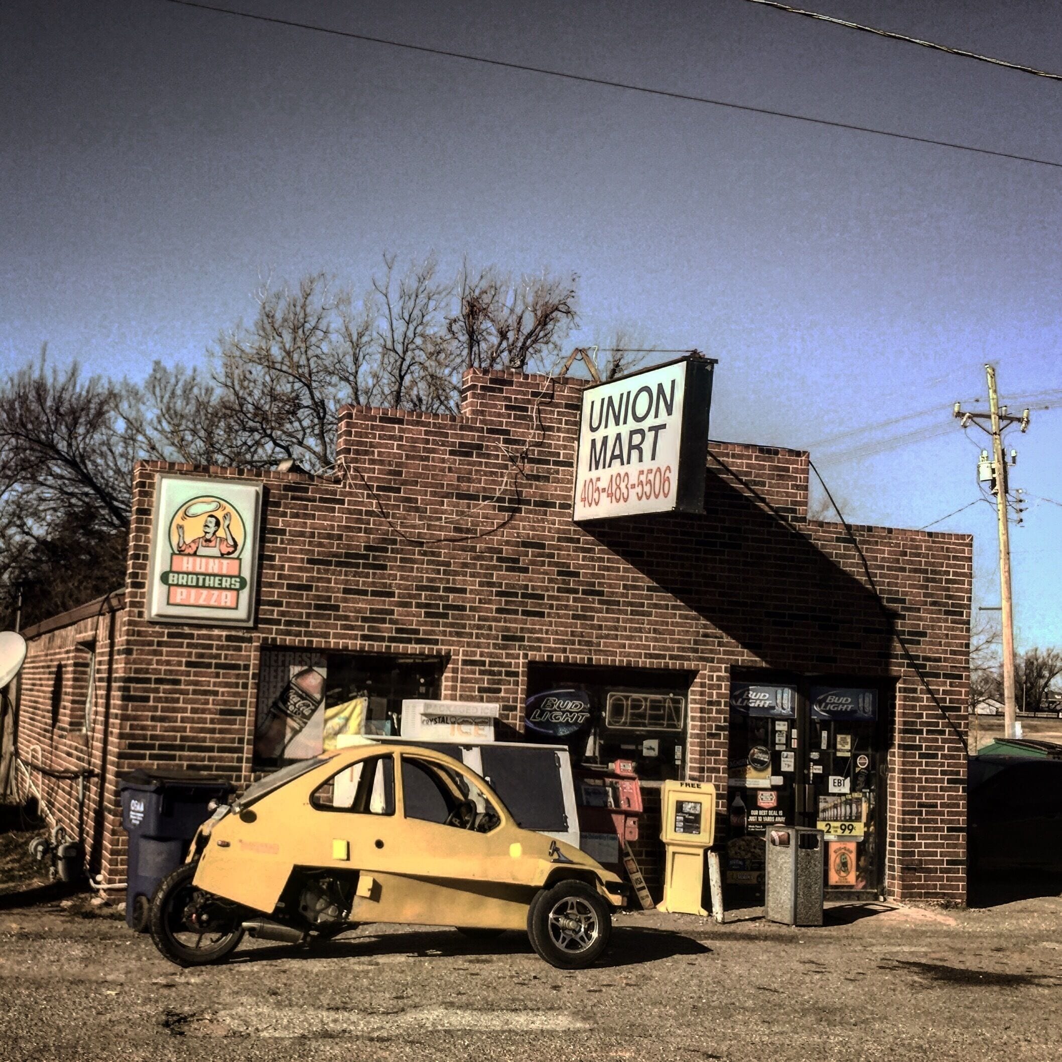 A small brick building with a sign for Union Mart and a yellow car parked in front.