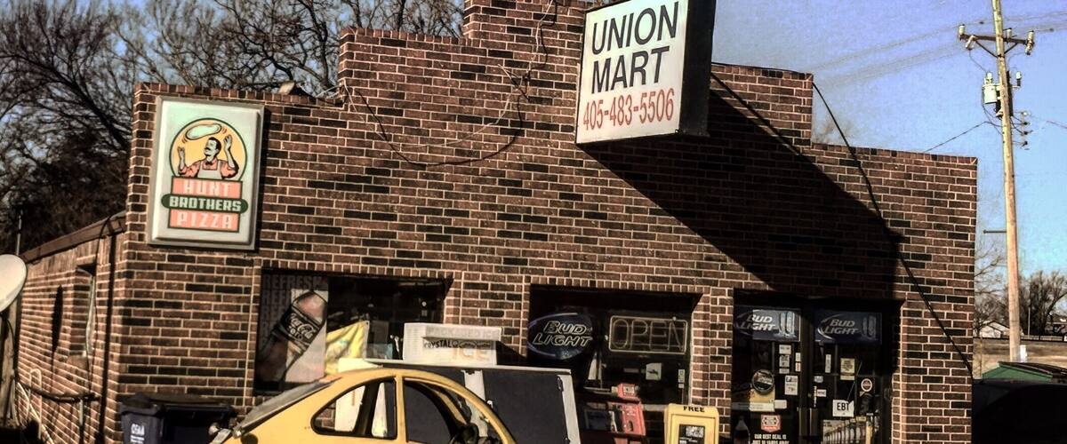 A small brick building with a sign for Union Mart and a yellow car parked in front.