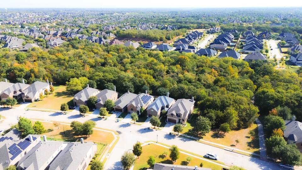 Net zero green community upscale neighborhood row of suburban houses large residential street, well-trimmed landscape, Bartonville and Argyle, Denton County, Texas, water tower background aerial