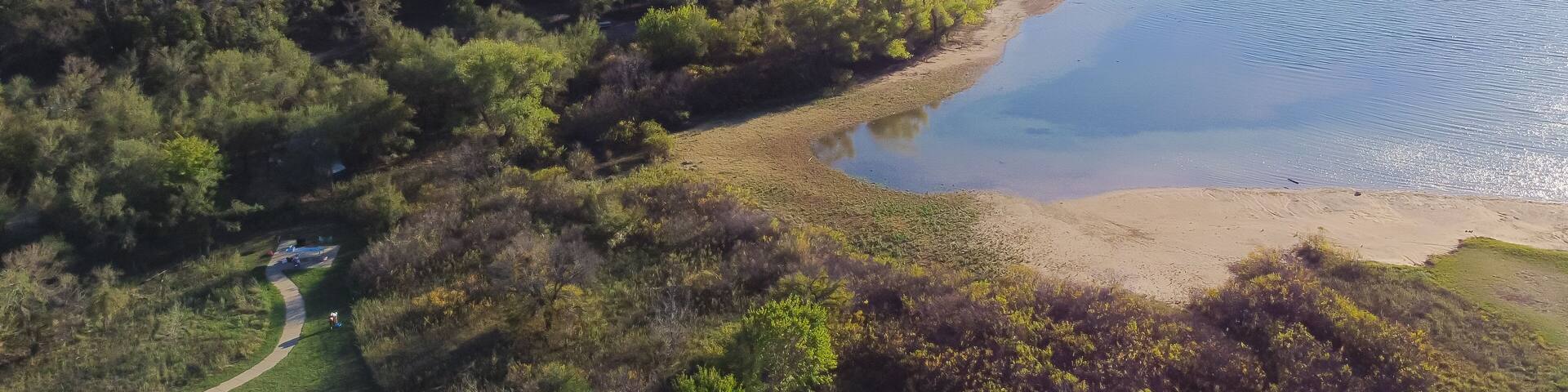 Aerial view a secondary point or hump surrounding by lush green trees and curved sandy shoreline at Isle du Bois Ray Roberts Lake State Park, remote primitive camping sites