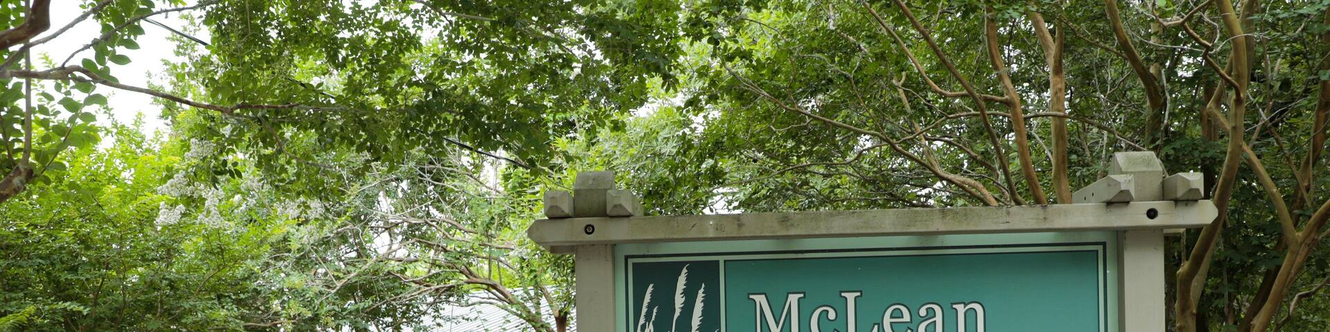 A sign for McLean Park with a picnic area and trees in the background.