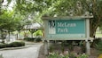 A sign for McLean Park with a picnic area and trees in the background.