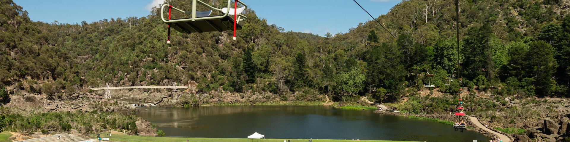 Um sistema de teleférico, uma piscina e um lago rodeado por colinas arborizadas.